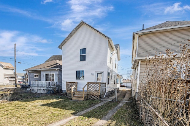 back of house featuring a lawn, fence, a deck, and a gate