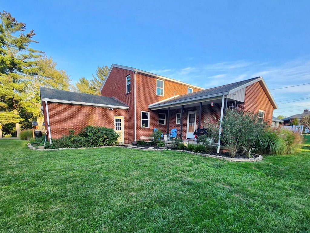 rear view of house with a lawn and brick siding