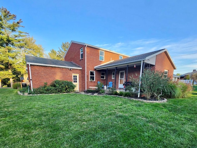 rear view of house with a lawn and brick siding