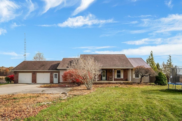 ranch-style home featuring brick siding, a trampoline, concrete driveway, a front yard, and a garage