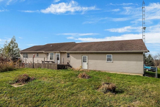 rear view of house with a yard, a deck, and fence