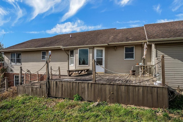 back of property with a wooden deck and roof with shingles