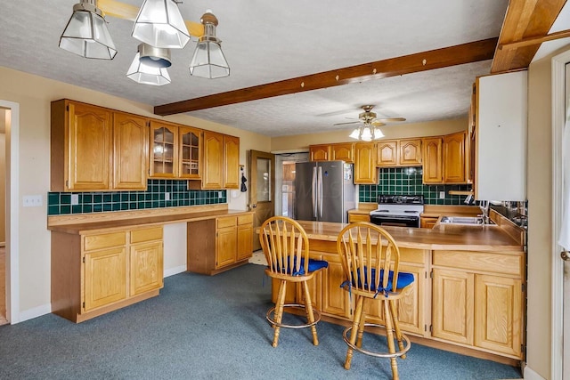 kitchen featuring a peninsula, freestanding refrigerator, a sink, electric stove, and beamed ceiling