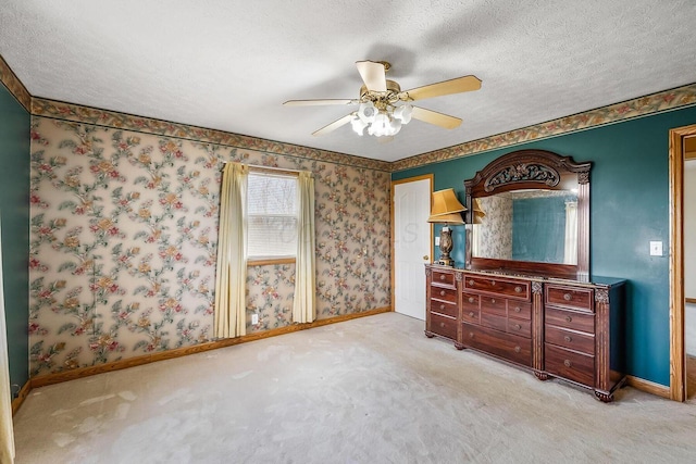 bedroom with wallpapered walls, light colored carpet, baseboards, and a textured ceiling