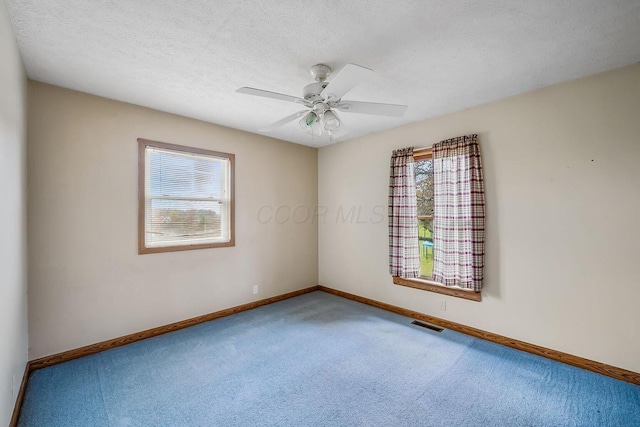 carpeted spare room with plenty of natural light, ceiling fan, a textured ceiling, and baseboards