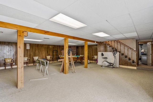 finished basement with billiards, wooden walls, carpet floors, a drop ceiling, and stairs
