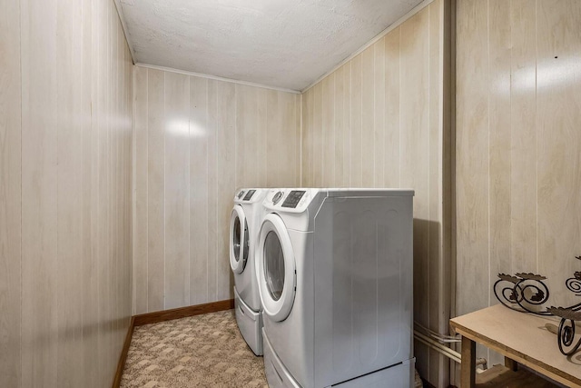 washroom featuring baseboards, washing machine and clothes dryer, laundry area, wood walls, and a textured ceiling