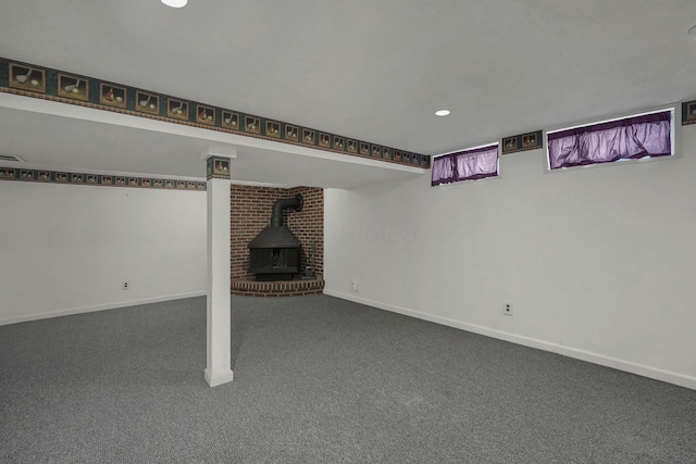 below grade area featuring visible vents, recessed lighting, carpet floors, baseboards, and a wood stove