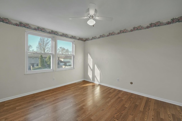 spare room featuring a ceiling fan, visible vents, wood finished floors, and baseboards