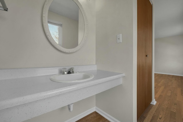 bathroom featuring wood finished floors, baseboards, and a sink