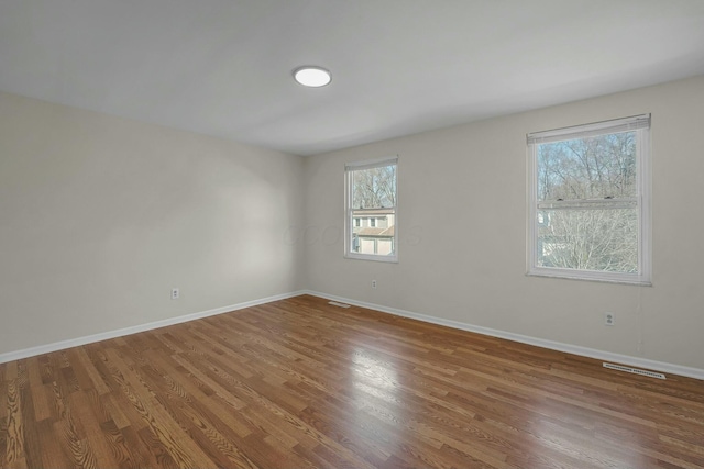 unfurnished room with visible vents, baseboards, and wood finished floors