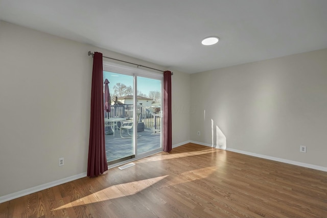 spare room featuring visible vents, baseboards, and wood finished floors