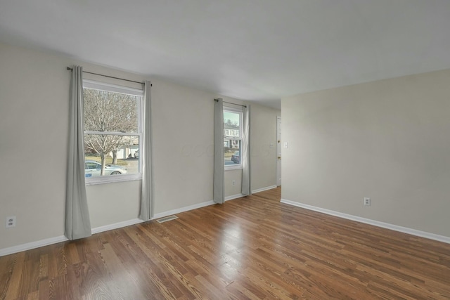 unfurnished room featuring visible vents, wood finished floors, and baseboards