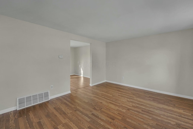 spare room featuring visible vents, baseboards, and wood finished floors