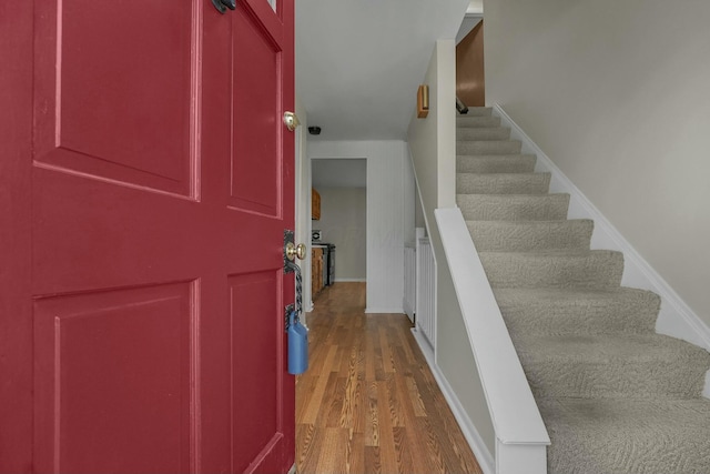 foyer with stairs, baseboards, and wood finished floors