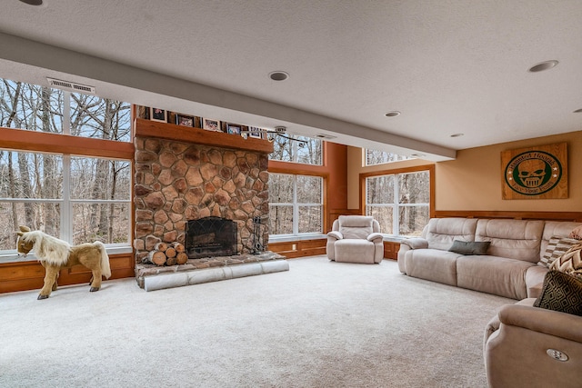 carpeted living area featuring visible vents, a textured ceiling, and a stone fireplace
