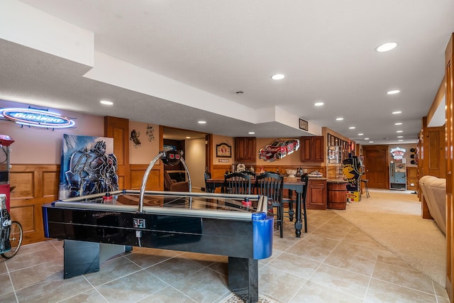 rec room with light tile patterned floors, recessed lighting, a wainscoted wall, and light carpet