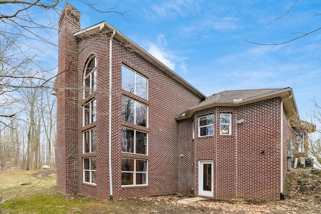 rear view of house with brick siding and a chimney