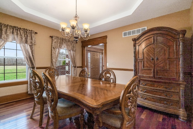 dining area with a tray ceiling, visible vents, plenty of natural light, and a chandelier