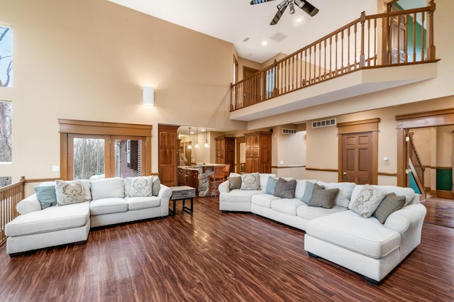 living area with visible vents, stairs, a high ceiling, a ceiling fan, and dark wood-style flooring