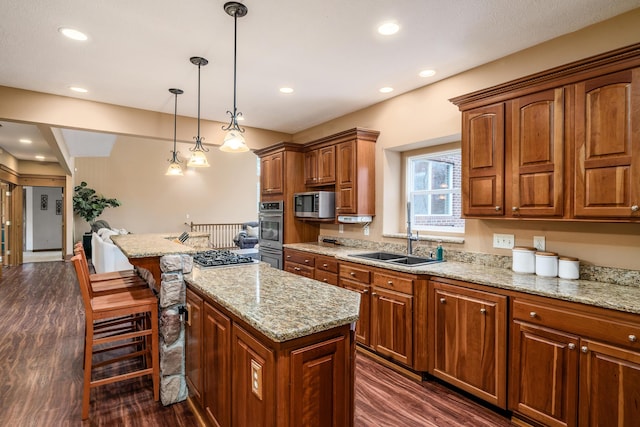 kitchen with stainless steel microwave, a center island, dark wood-type flooring, light stone countertops, and a sink