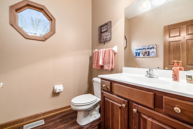 bathroom featuring visible vents, toilet, wood finished floors, baseboards, and vanity
