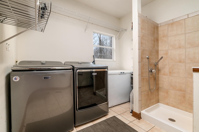 clothes washing area featuring light tile patterned flooring, laundry area, and independent washer and dryer