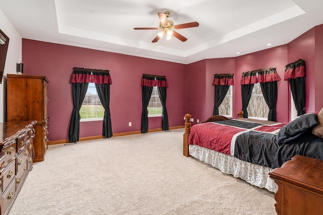 bedroom with a tray ceiling, baseboards, and light colored carpet