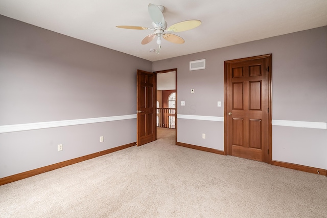 spare room with visible vents, baseboards, light colored carpet, and a ceiling fan