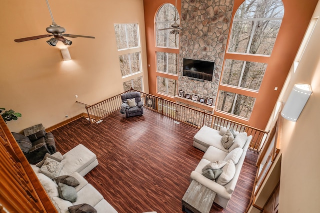 living area featuring baseboards, a high ceiling, wood finished floors, and a ceiling fan