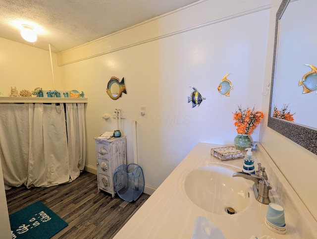 bathroom with a textured ceiling, wood finished floors, and a sink