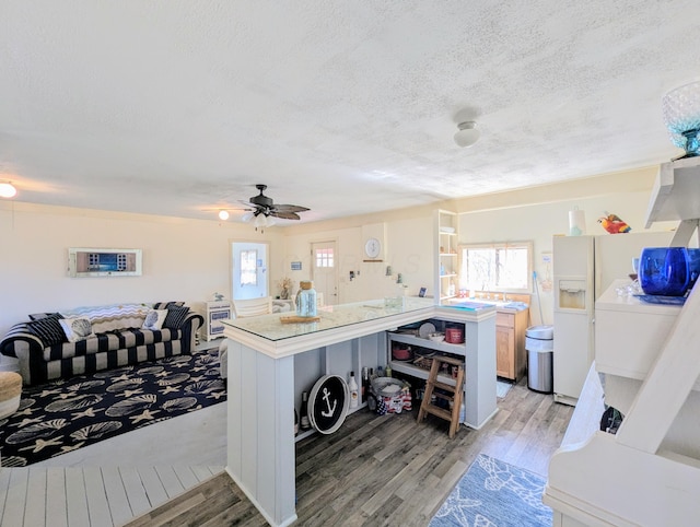 kitchen with light wood-style flooring, a textured ceiling, light countertops, and white fridge with ice dispenser