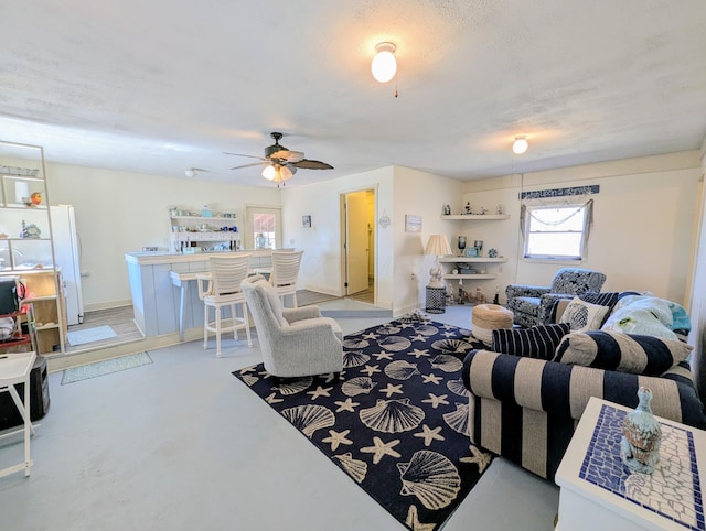 living room with baseboards, finished concrete flooring, and a ceiling fan