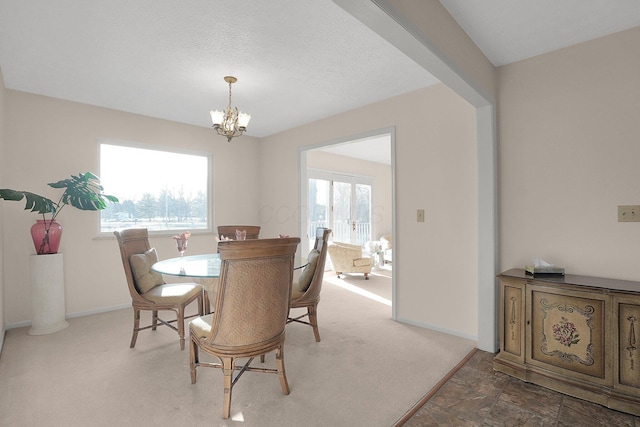 carpeted dining room featuring a notable chandelier, baseboards, and stone finish flooring