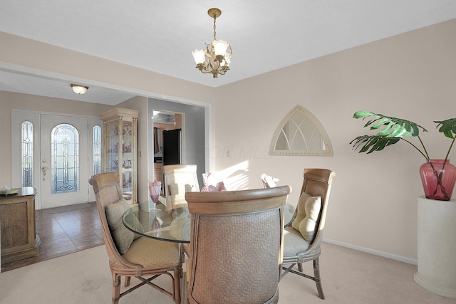 dining space featuring light colored carpet, baseboards, and a notable chandelier