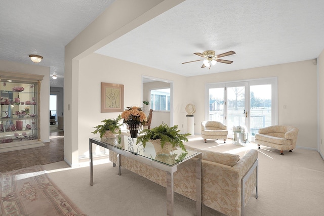 living room with light carpet, baseboards, a textured ceiling, and ceiling fan