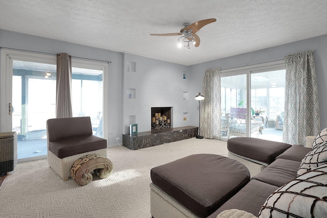 carpeted living area with a textured ceiling and ceiling fan