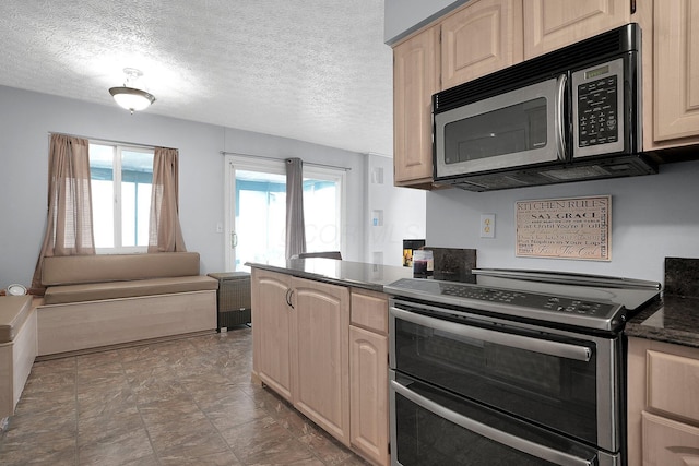 kitchen featuring double oven range, open floor plan, and light brown cabinetry