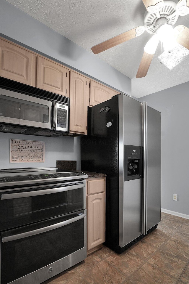 kitchen with ceiling fan, light brown cabinetry, appliances with stainless steel finishes, a textured ceiling, and dark countertops