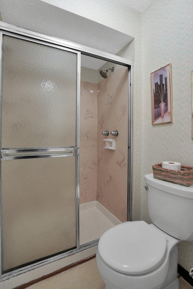 bathroom featuring wallpapered walls, toilet, and a stall shower