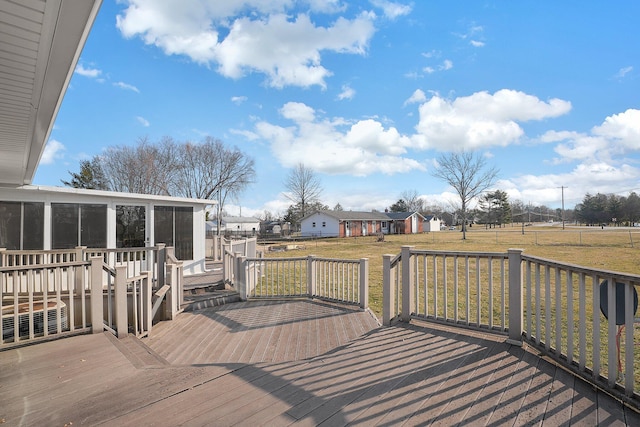 wooden deck featuring a lawn and a sunroom