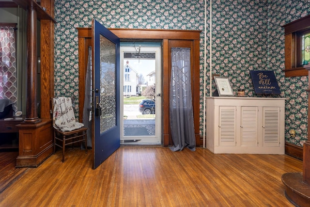 foyer entrance featuring wood finished floors and wallpapered walls