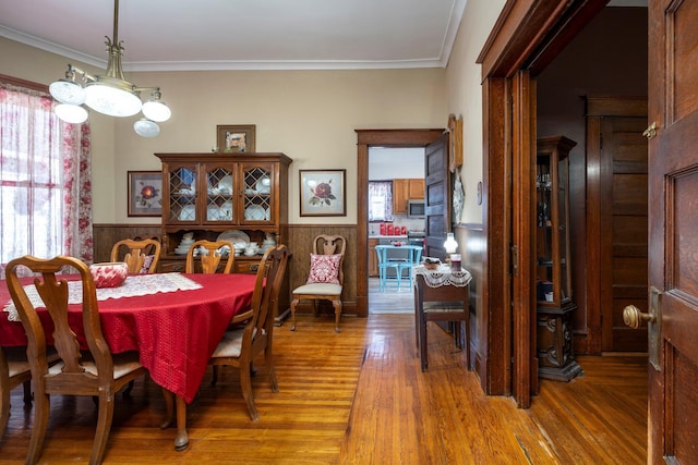 dining room with wood finished floors, wainscoting, and ornamental molding