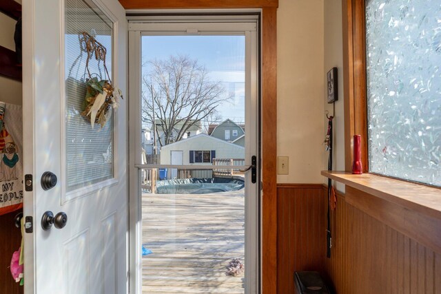 doorway to outside featuring wainscoting and wood walls