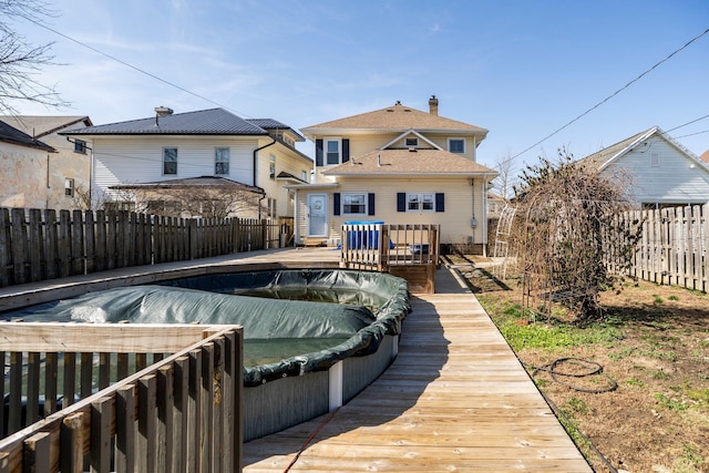 back of house featuring a fenced backyard, a chimney, a hot tub, and a wooden deck