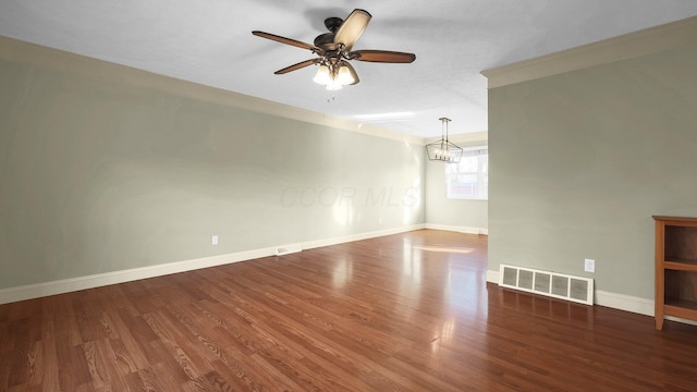 unfurnished room with visible vents, baseboards, ornamental molding, ceiling fan with notable chandelier, and wood finished floors