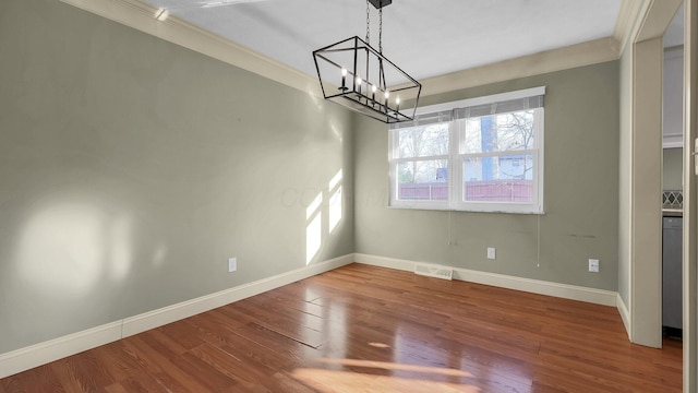 unfurnished dining area with wood finished floors, visible vents, baseboards, an inviting chandelier, and crown molding