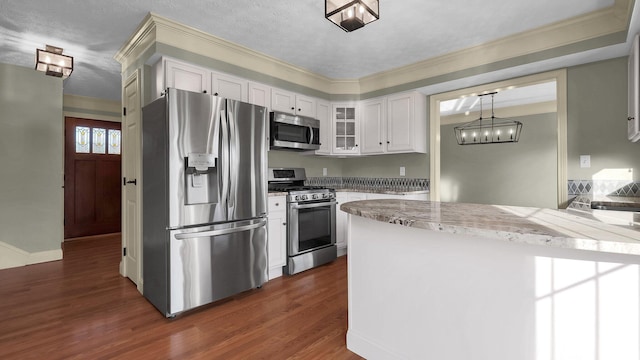 kitchen with a peninsula, dark wood-type flooring, glass insert cabinets, appliances with stainless steel finishes, and white cabinetry