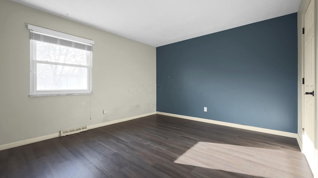 unfurnished room with wood finished floors, visible vents, and baseboards