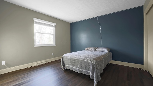 bedroom with dark wood-type flooring, baseboards, visible vents, and a textured ceiling